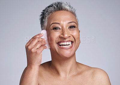Buy stock photo Beauty, gua sha and skincare of a senior woman in studio for dermatology, cosmetics and facial massage on a grey background. Face portrait of a mature model happy about skin results with rose quartz