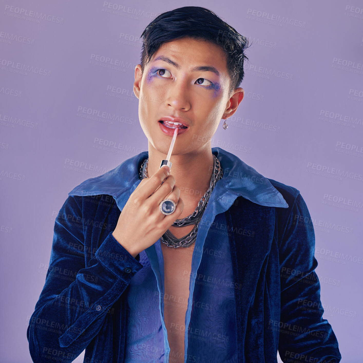 Buy stock photo Beauty, makeup and lgbt Asian man in studio on purple background using cosmetics, beauty products and lipstick. Creative, fashion and queer or lgbtq male model with lip gloss, eyeshadow and style