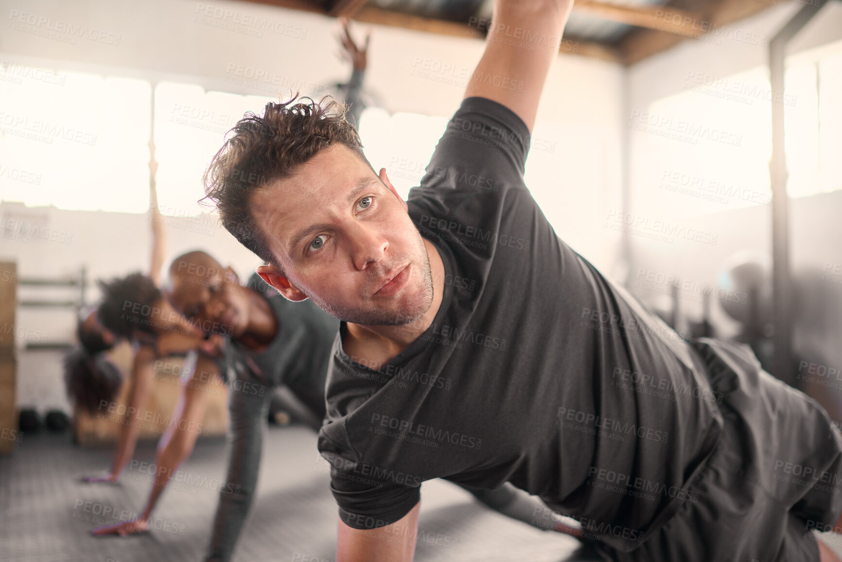 Buy stock photo Fitness, personal trainer and group doing a side plank exercise together for strength in the gym. Strong, sports and strong athletic team doing a intense workout with a coach or leader in health club