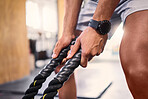 Hands, fitness and battle ropes with a sports man training for cardio or endurance in a gym workout. Grip, heavy ropes and exercise with a male athlete holding equipment for a healthy, strong body