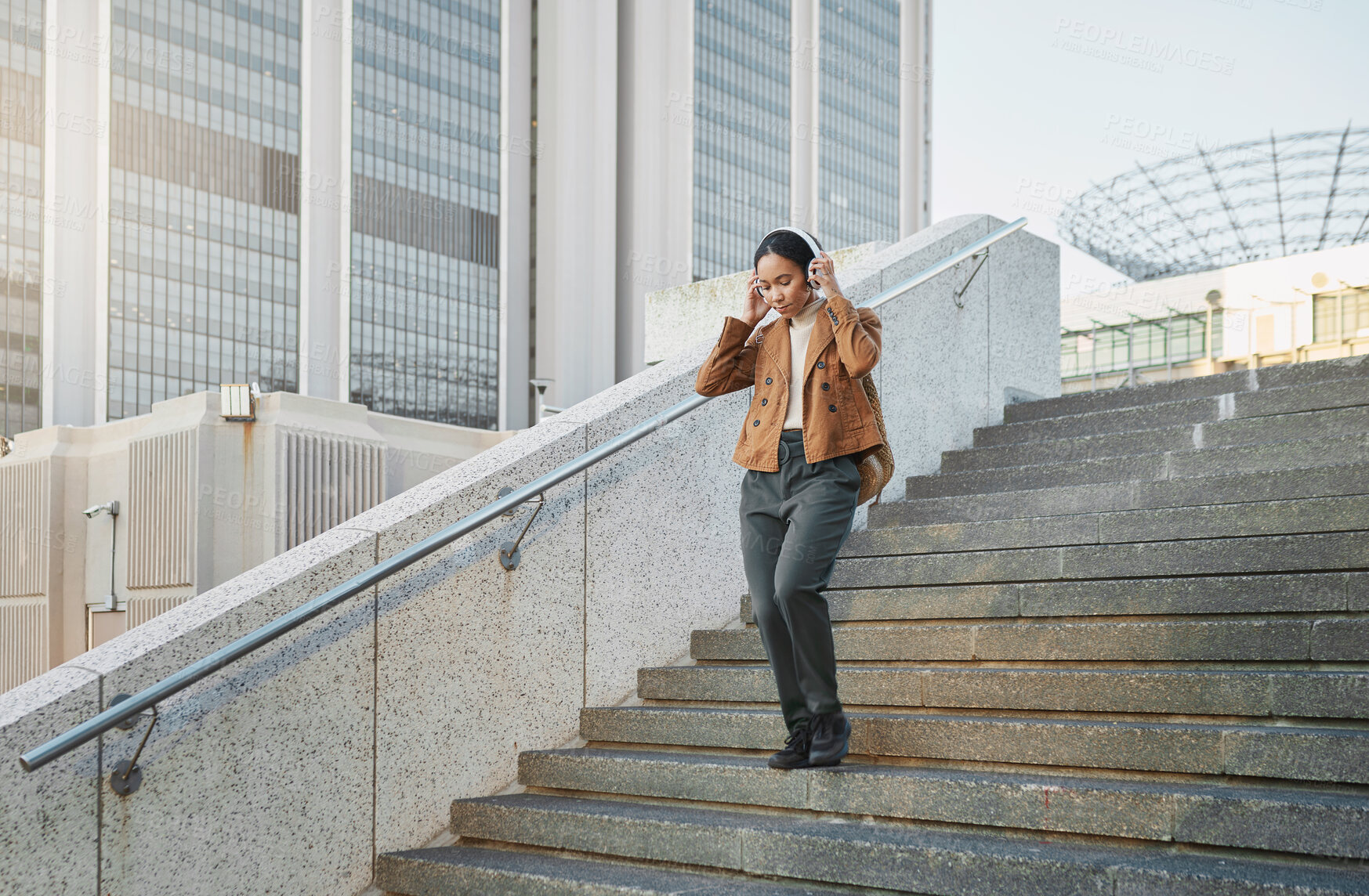 Buy stock photo Music, stairs and city with a business black woman walking outdoor while using headphones for streaming audio. Steps, commute and listening with a female employee streaming audio in an urban town