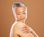Face, skincare and antiaging with a mature woman in studio on a brown background for natural skincare. Wellness, cosmetics and shoulder with a senior female posing to promote a beauty product