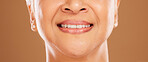 Teeth, dental and senior woman in studio isolated on a brown background. Oral care, wellness or closeup smile of elderly female model with natural looking veneers for beauty and healthy tooth hygiene