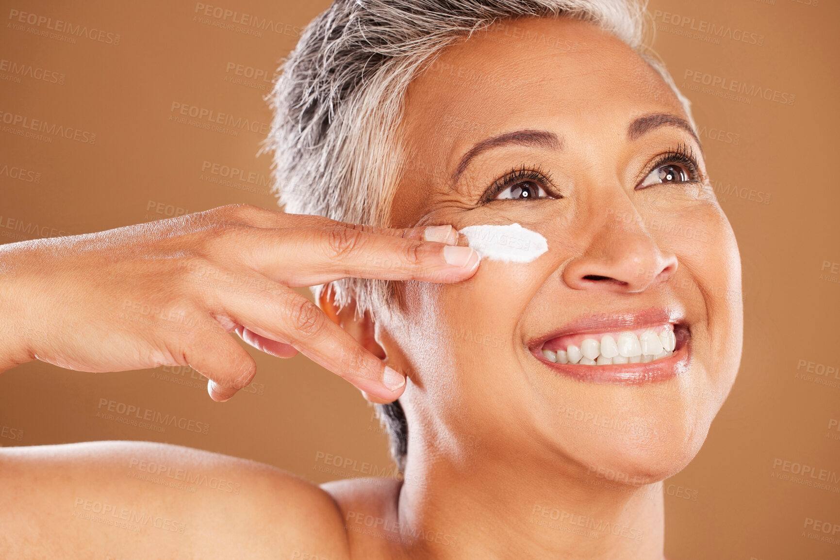 Buy stock photo Mature woman, face or skincare product grooming on studio background in dermatology routine, health wellness or collagen treatment. Zoom, happy smile or Indian beauty model and sunscreen facial cream