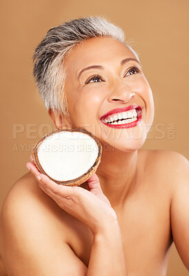 Buy stock photo Coconut, skincare, face and diet wellness keeps her happy and healthy for skin healthcare, eat healthy fruit with nutrition. Portrait of a beauty senior woman in studio against a brown background 