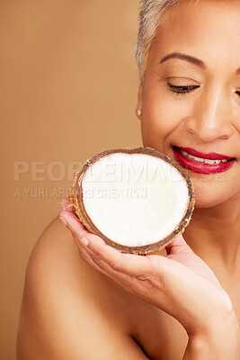 Buy stock photo Beauty, skincare and coconut with a senior woman in studio on a brown background to promote natural antiaging care. Cosmetics, moisture and hydration with a mature female posing with a fruit half