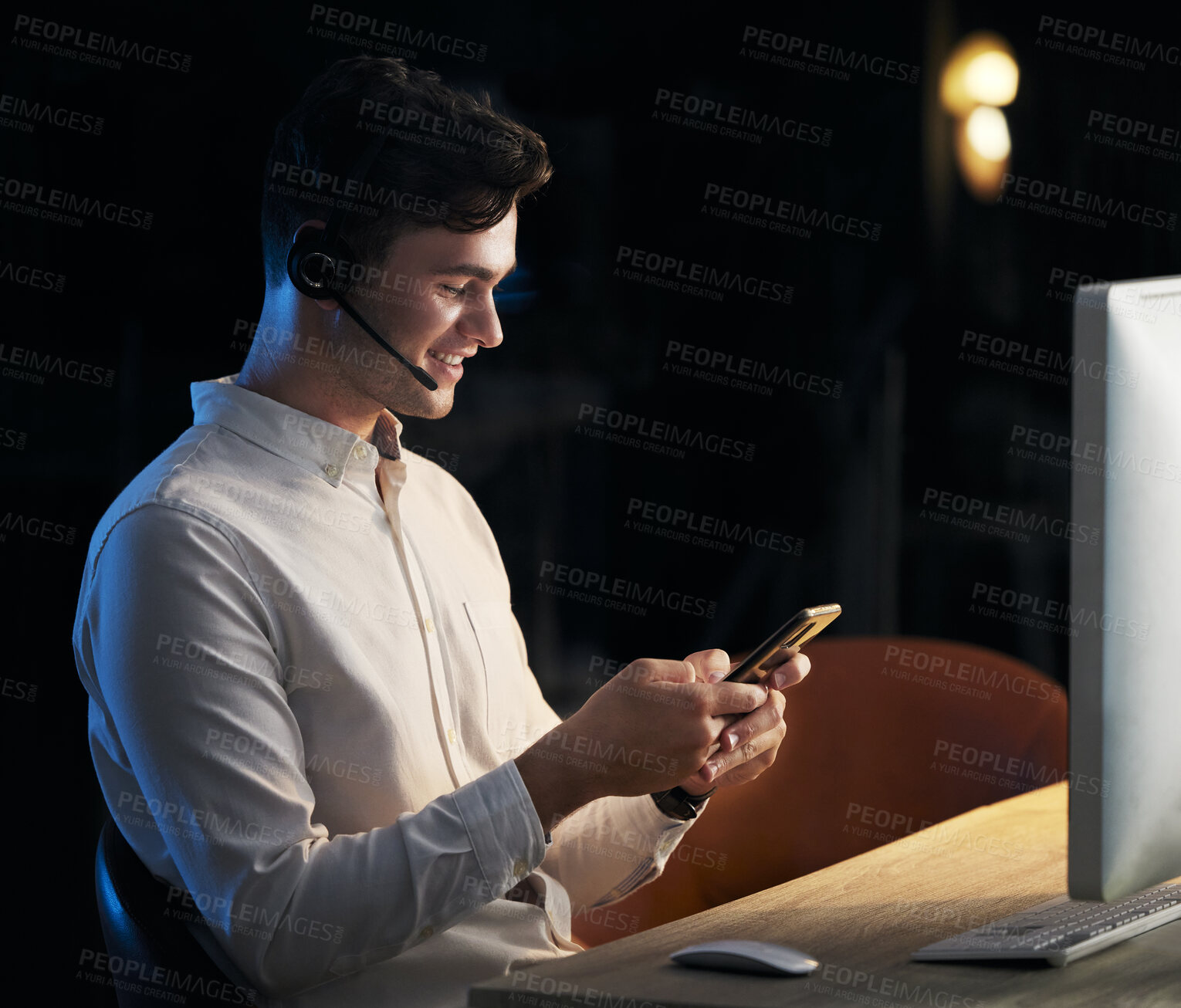 Buy stock photo Man, headphones and smartphone in call center office at night for business communication online. Businessman, crm telemarketing and online customer service agent on company phone happy at work desk