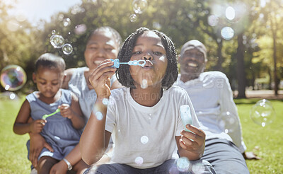 Buy stock photo Happy, nature and black family blowing bubbles while playing, bonding and enjoying summer in the park. Happiness, father and mother with children having fun together in a green garden in South Africa