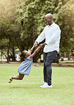 Black man, spinning child and happy at park for funny game, play or bonding outdoor in summer. Father, girl and swing with hands on lawn, grass or garden with love, care or happiness in black family