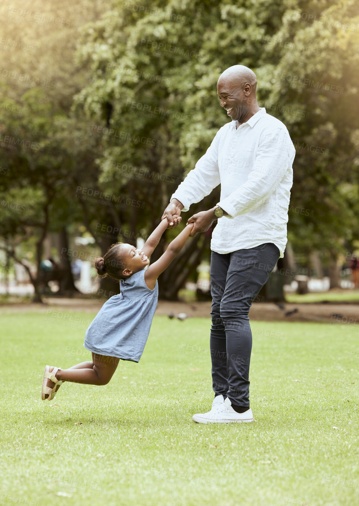 Buy stock photo Black man, spinning child and happy at park for funny game, play or bonding outdoor in summer. Father, girl and swing with hands on lawn, grass or garden with love, care or happiness in black family