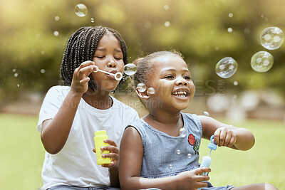 Buy stock photo Black kids, children and blowing bubbles at park, having fun and bonding. Girls, happy sisters and playing with soap bubble toys, relax and enjoying garden together outdoors in nature on grass
