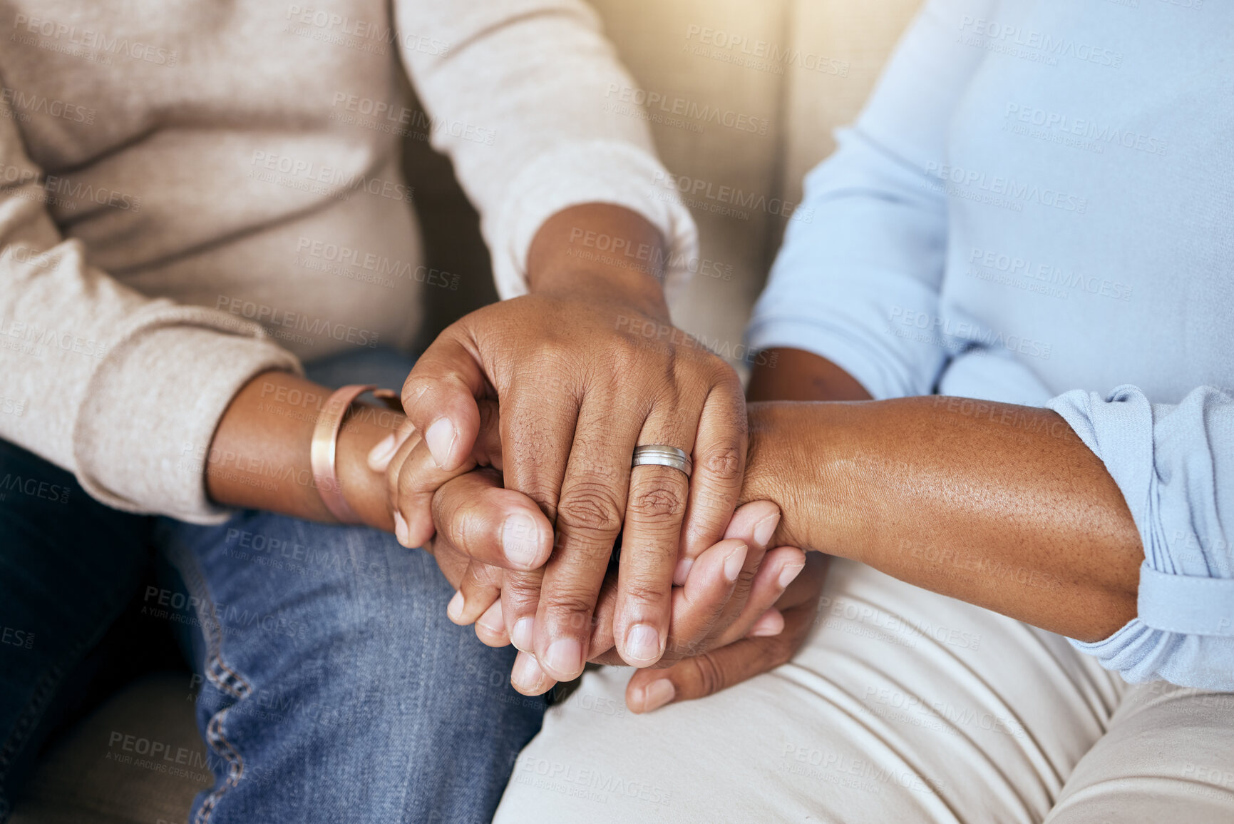 Buy stock photo Support, love and closeup of people holding hands for comfort while sitting on a sofa together. Compassion, sympathy and friends praying, bonding and healing together in the living room of a house.