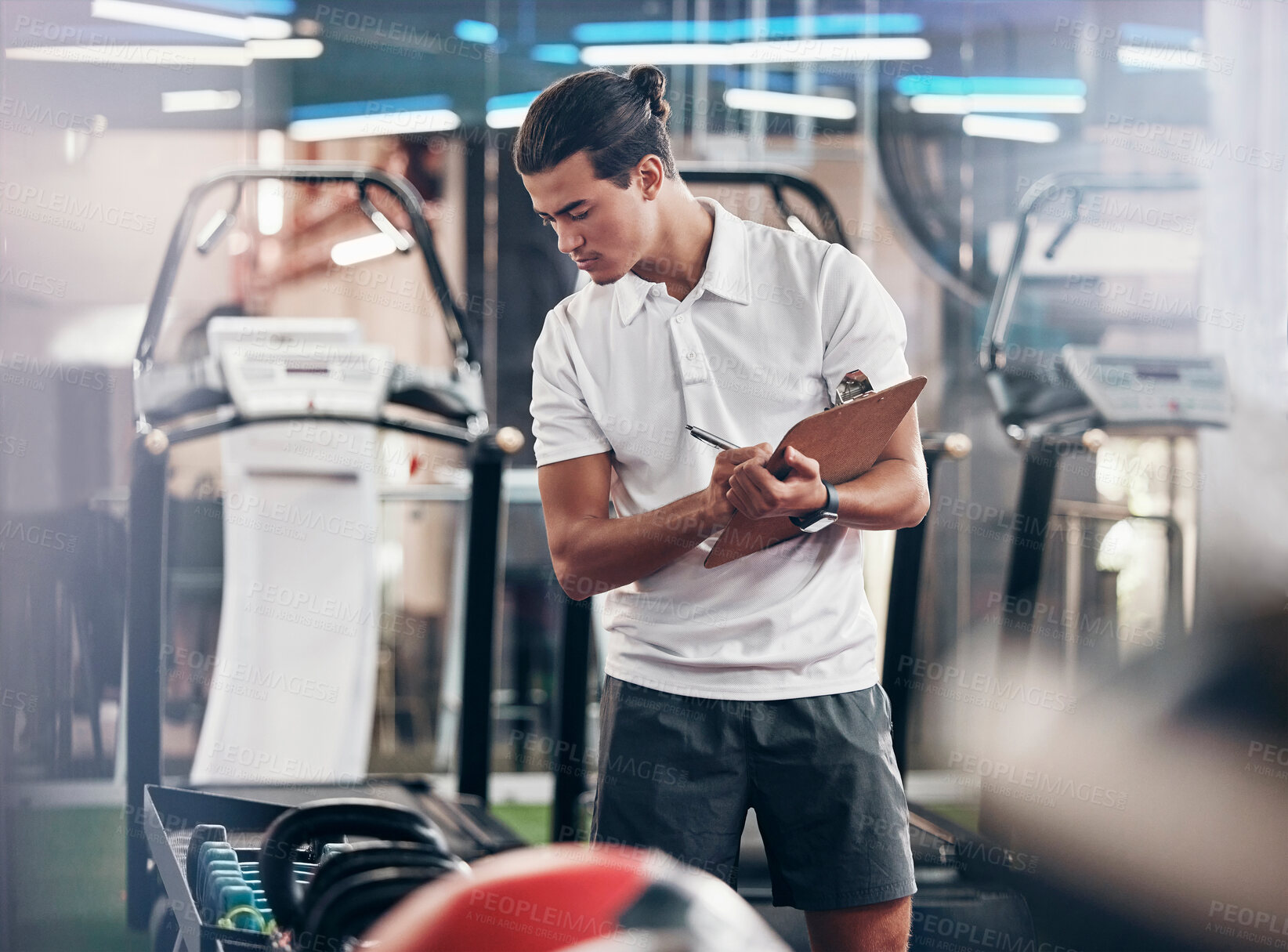 Buy stock photo Gym, coach and clipboard with a man manager checking equipment in the gym and writing notes. Leader, personal trainer and athletic male checking exercise weights in a healthclub to prepare