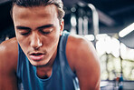 Tired, gym and fatigue man taking a break from workout, training or exercising inside a wellness club. Young athlete or cardio guy bending after his fitness strength or muscle exercise for health