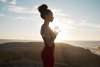 Buy stock photo Wellness, yoga and meditation with black woman and fitness at the beach, calm and peace in the sun with lens flare. Zen, mindfulness and healthy mindset, athlete on rocks by the ocean for exercise. 