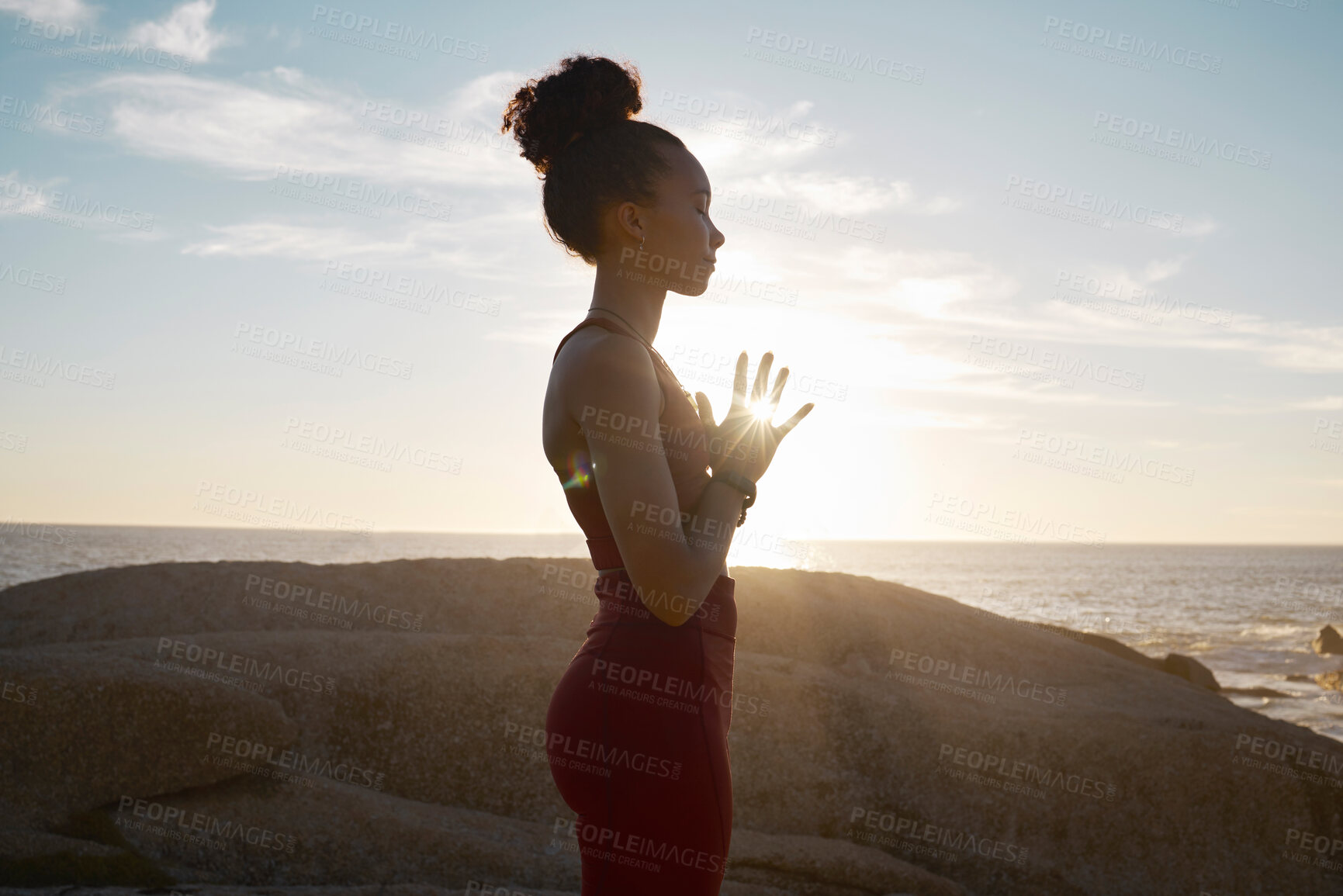 Buy stock photo Wellness, yoga and meditation with black woman and fitness at the beach, calm and peace in the sun with lens flare. Zen, mindfulness and healthy mindset, athlete on rocks by the ocean for exercise. 