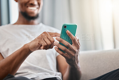 Buy stock photo Hands, phone and social media with a black man typing a text message while sitting on a sofa in his home. Mobile, communication and networking with a male chatting from the living room in his house