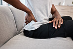 hand, back pain and woman at home on the couch after injury or accident with a bad muscle. Bruise, strain and injured female with sore back on a living room sofa for rest after body emergency