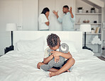 Sad, fight and boy on the bed with parents in conflict depression, anxiety and stress in their family home. Fear, scared and child with a teddy bear hug while mother and father talk about divorce