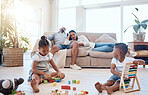 Parents on couch, children and playing with toys on weekend to relax, fun and bonding in lounge. Family, mother and father with brother, sister or play educational games, happiness and in living room