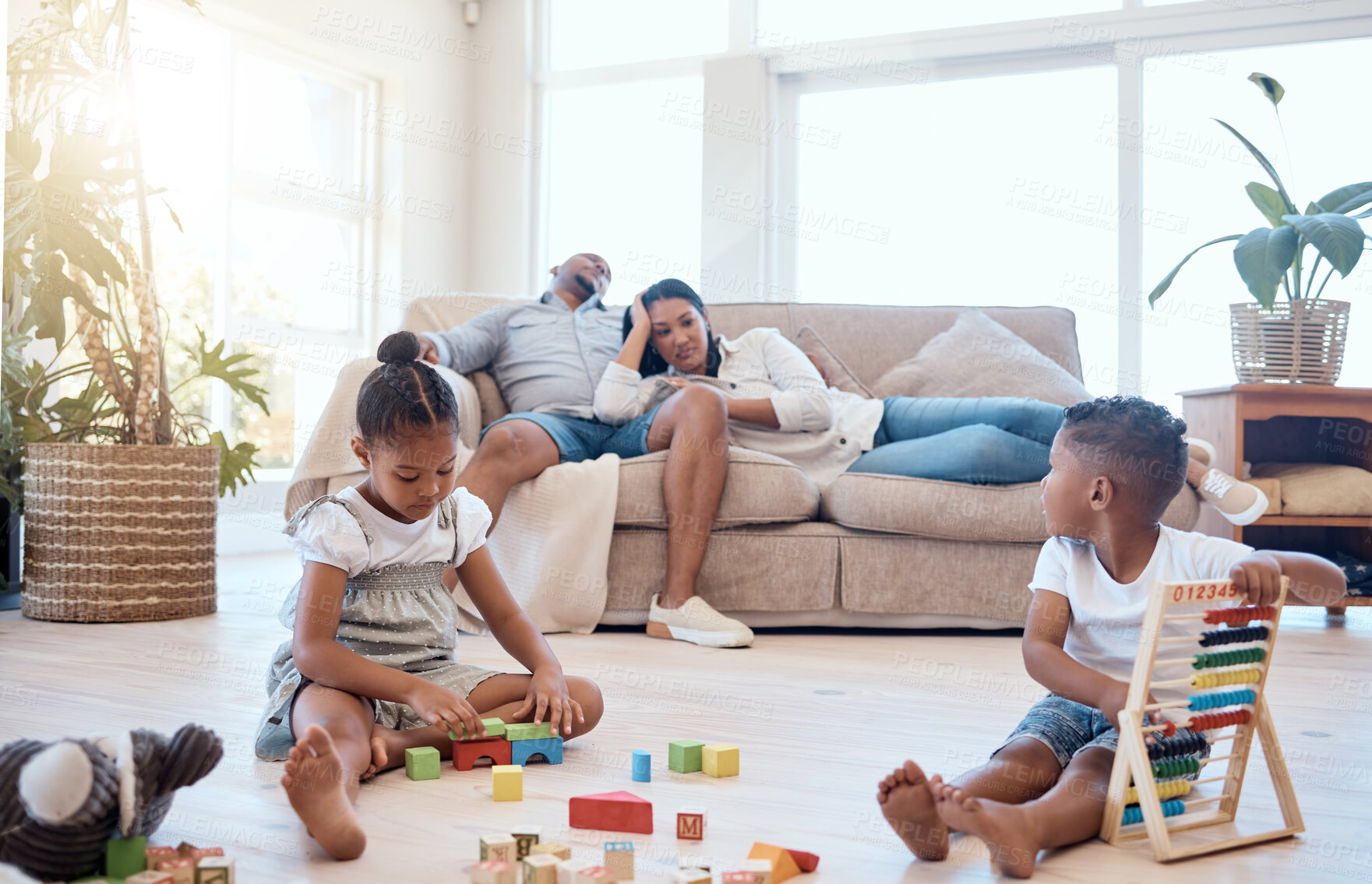 Buy stock photo Tired parents on couch, children and playing with toys on weekend to relax, for bonding and sleepy in lounge. Family, mother and father with brother, sister and play educational games and exhausted.