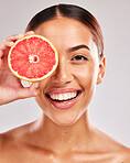 Grapefruit, portrait and black woman in studio for skincare, detox and healthy glow with smile for vegan product promotion. Beauty young black model with vitamin c fruits on eye for skin care shine