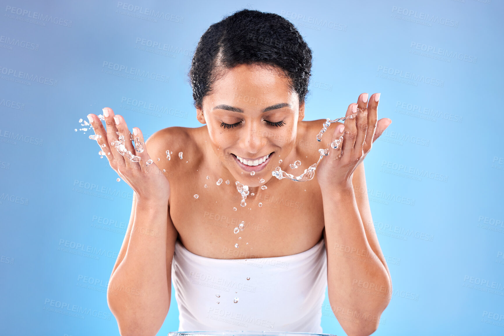 Buy stock photo Black woman, cleaning face with water, skincare and wellness with smile against a mockup studio blue background. Female model washing face, beauty and happy for skin health, happiness or water splash