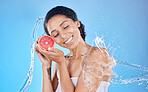 Shower, water and grapefruit with a model black woman in studio on a blue background with a splash for hygiene. Health, water splash and skincare with an attractive young female holding natural fruit