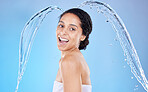 Water, splash and hygiene with a model black woman in the studio shower on a blue background for hygiene. Portrait, face and water splash with an attractive young female cleaning in the bathroom