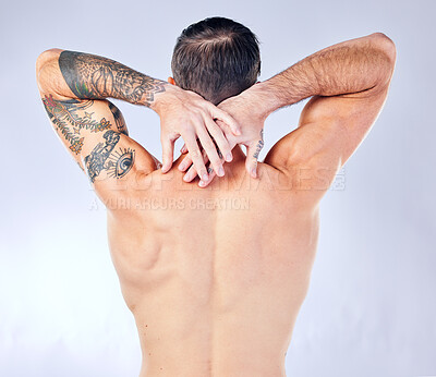 Buy stock photo Body care, wellness and back view of a man in a studio with muscles, tattoos and fit body. Fitness, warm up and bodybuilder or muscular model doing a stretching exercise isolated by a gray background