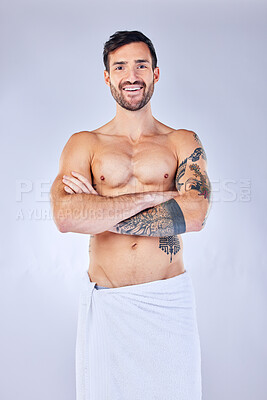 Buy stock photo Shower, towel and hygiene with a topless man in studio on a gray background for wellness or body care. Portrait, cleaning and tattoo with a handsome young male standing arms crossed in a bathroom