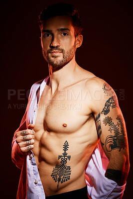Buy stock photo Fashion, sexy and portrait of a man in a studio with muscles, body and tattoos for body care or fitness. Handsome, young and edgy model from Canada posing with bare chest isolated by dark background.