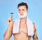 Shave, razor and man with shaving cream and towel for grooming, beauty and skincare against blue studio background. Clean, hygiene and face product in hand with fresh skin and hair removal mockup.