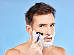 Facial, shave and razor portrait of man for hygiene, cleaning and self care routine for healthy skin. Wellness, health and face of model with beard foam on blue studio  mock up for advertising.

