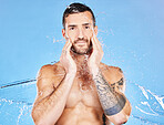 Water, splash and hydration with a man model in studio on a blue background for hygiene or skincare. Relax, wellness and shower with a handsome young male cleaning his body or skin in the bathroom