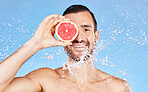 Grapefruit, skincare and man in studio portrait with water splash for natural health, glow and detox. Happy model with healthy food, vitamin c fruits and facial or face shower water drops cleaning