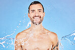 Skincare, portrait and water splash of man in studio isolated on a blue background. Health, cleaning and male model from Canada bathing and washing for wellness, body care and fresh beauty routine.
