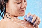 Hand, soap and shower with a woman cleaning her shoulder in studio on a blue background for hygiene. Water, skincare and wellness with a young female washing her body for hydration in the bathroom