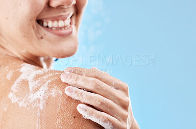 Buy stock photo Shower, soap and smile of a woman grooming body for health, skincare and wellness against a blue mockup studio background. Water, cleaning and hand of a model with foam on shoulder and mock up space