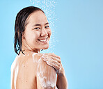 Shower, woman and hygiene for wellness, smile and happy with cleaning, water splash and against blue studio background. Portrait, young female and lady doing scrub, washing and health with happiness.