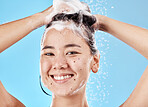 Woman, shampoo and shower in studio portrait with hair care, cleaning and smile by blue background. Model, hair and splash with foam, soap or water for self care, cosmetics and beauty with happiness