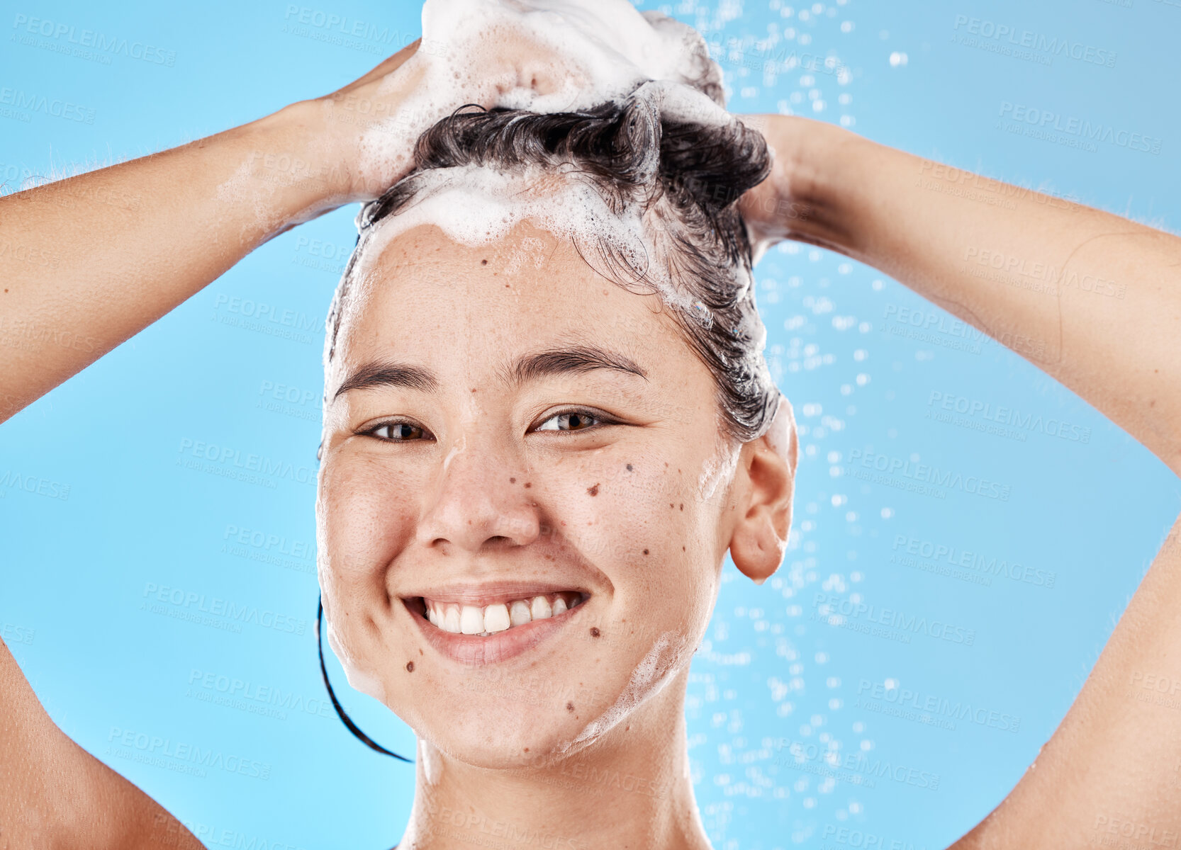 Buy stock photo Woman, shampoo and shower in studio portrait with hair care, cleaning and smile by blue background. Model, hair and wellness with foam, soap or water for self care, cosmetics or beauty with happiness