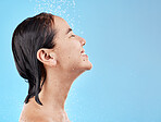 Asian woman, shower and water for cleaning, smile and happy in blue studio mockup background. Model, clean and showering face, body and hygiene, skincare or cosmetic beauty in bathroom with happiness
