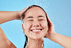 Woman, shower and smile for skincare hygiene, wash or cleanse against a blue studio background. Happy female face smiling in satisfaction for clean wellness, cosmetics or healthy hair care treatment