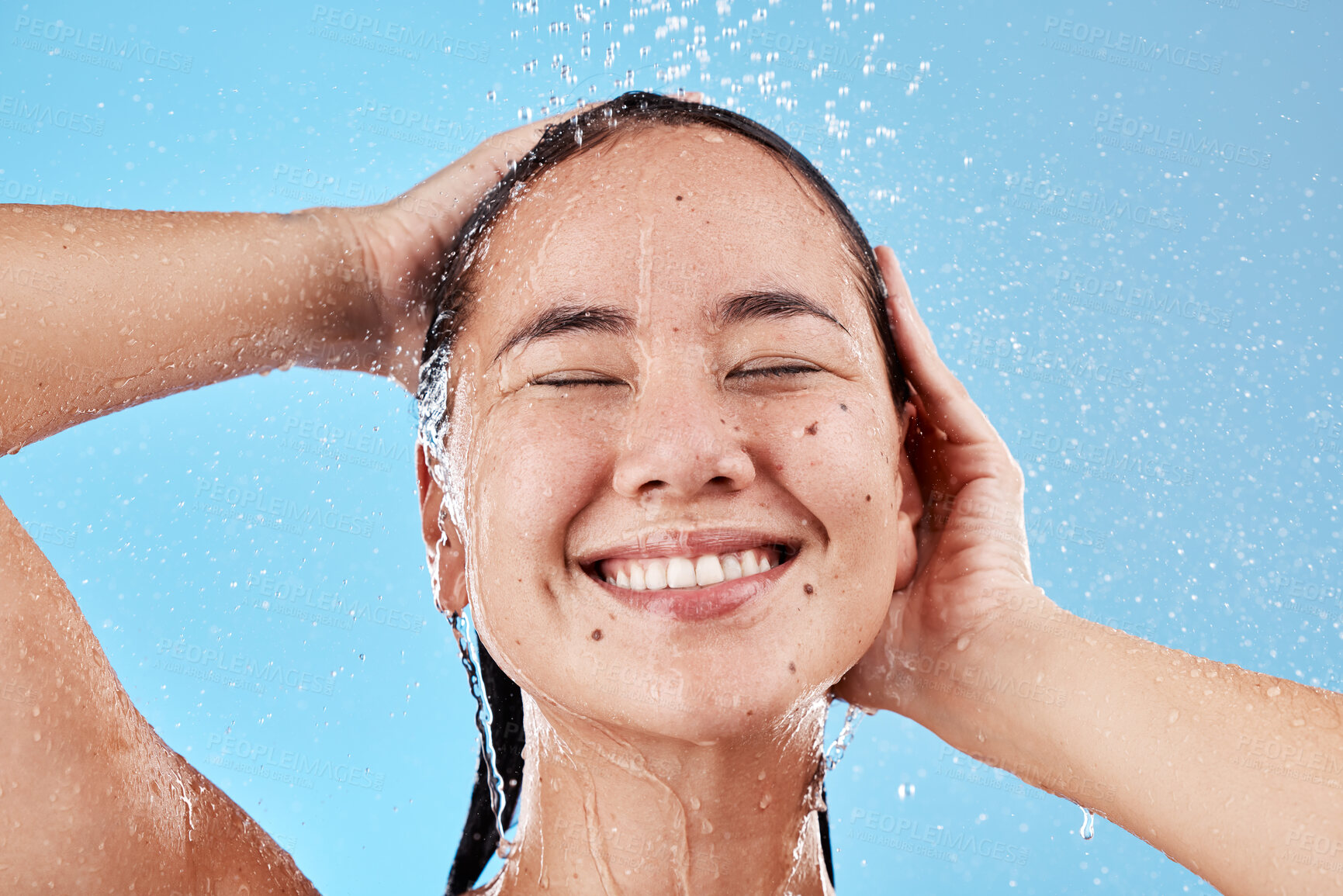 Buy stock photo Woman, shower and smile for skincare hygiene, wash or cleanse against a blue studio background. Happy female face smiling in satisfaction for clean wellness, cosmetics or healthy hair care treatment