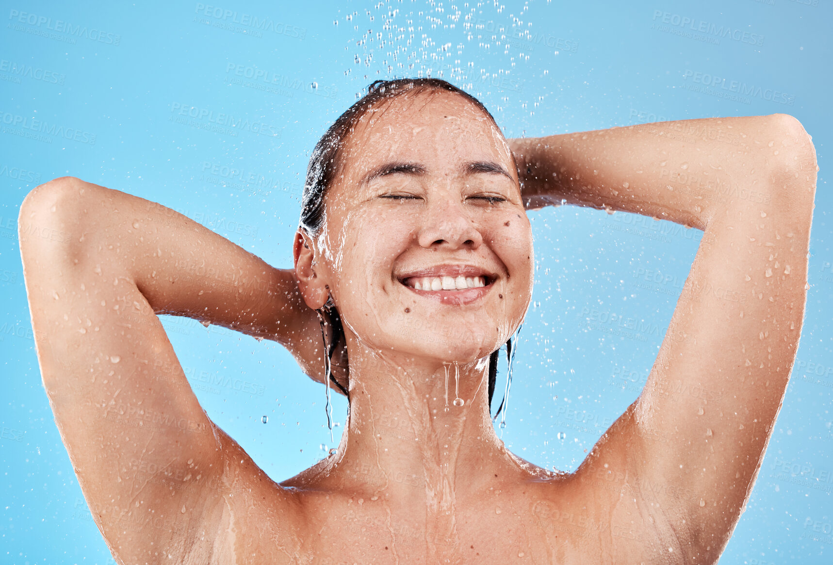 Buy stock photo Shower, skincare and woman in studio for cleaning, wellness and beauty water splash blue mockup. Happy, young and hygiene asian model with water drops in bathroom for face skin care morning routine