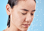 Shower, woman and water for wellness, health and hygiene for body care, wet and against blue studio background. Drops, healthy female or girl washing, clean or bathroom grooming for cleaning or relax