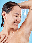 Skincare, cleaning and woman in shower in studio isolated on a blue background. Water splash, hygiene and healthy female model from Canada bathing and washing for beauty, body care and wellness.


