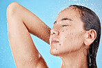 Skincare, beauty and woman in shower on blue background, haircare and hygiene routine in the morning. Model in water splash relax, cleaning hair and face with running water for clean fresh lifestyle.