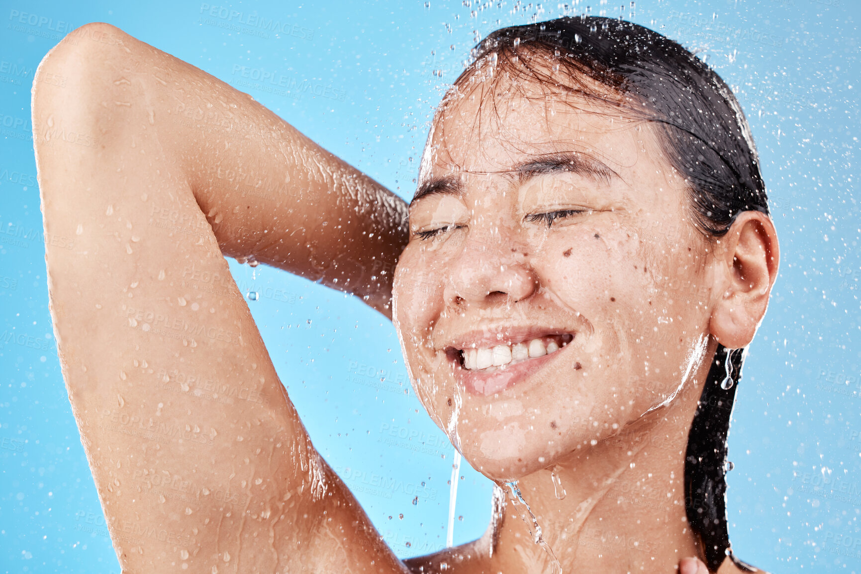 Buy stock photo Shower, woman and water for health, wellness and hygiene for body care, clean and against blue studio background. Drops, healthy girl or female washing, relax or bathroom grooming for cleaning or wet